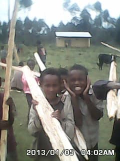 Children carrying wooden fence posts contributed by the community